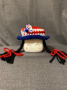 a small doll wearing a red, white and blue hat with tassels on it's head