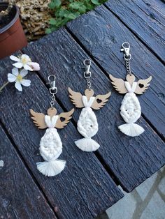 four different key chains with birds on them sitting on a wooden table next to flowers