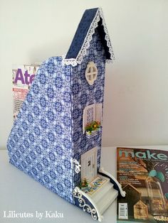 a blue and white doll house sitting on top of a table next to a magazine