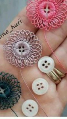 four different types of buttons are being held in someone's hand with string and thread