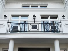 a balcony with black wrought iron railings and two lamps on the top of each balconies