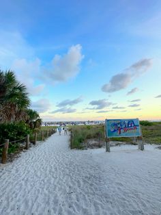 people are walking on the beach near a sign that says, happy birthday to you