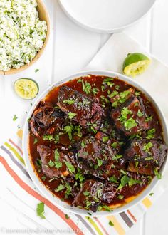 a white bowl filled with meat and garnished with cilantro