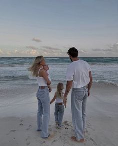 a man, woman and child are standing on the beach with their hands in each other's pockets