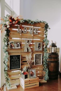 a wooden sign that says love is written on it and surrounded by photos, flowers and greenery