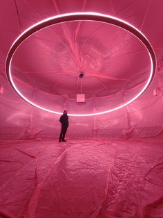 a man standing in the middle of a room with pink light coming from its ceiling