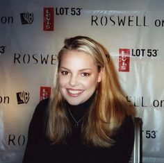 a woman standing in front of a red and white backdrop with the name roswell on it