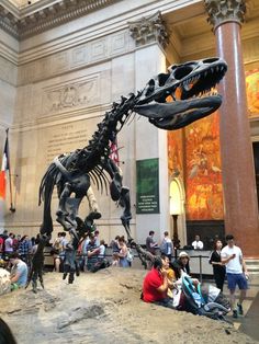 a large dinosaur skeleton in a museum filled with people