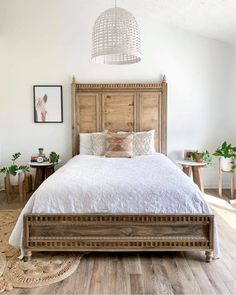 a bedroom with white walls and wooden bed frame, wood headboard, and rug on the floor