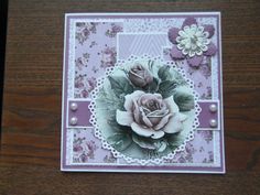 a close up of a card on a wooden table with flowers and lace around it