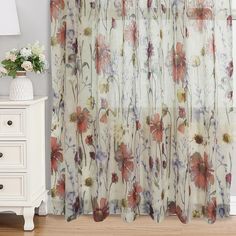 a curtain with flowers on it in front of a white dresser