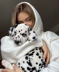 a woman holding a dalmatian puppy wrapped in a blanket