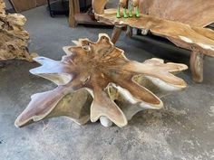 a wooden bench sitting on top of a cement floor next to a tree trunk table