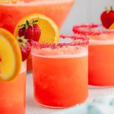 two glasses filled with lemonade and strawberries on top of a blue tablecloth