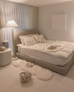 a bedroom with a large bed and white rugs on the floor next to a lamp