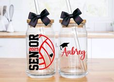 two personalized glass jars with black bows on the lids are sitting on a table