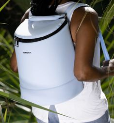 a woman carrying a white backpack through tall grass