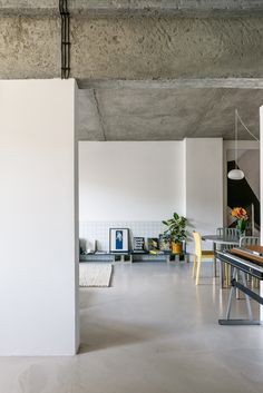 an empty room with white walls and yellow chairs in the center, next to a dining table