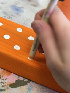 a person holding a pencil in their right hand and writing on a piece of wood