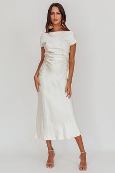 a woman wearing a white dress with short sleeves and an asymmetrical neckline