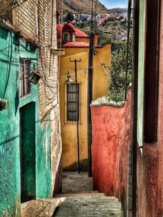 an alley way with colorful buildings and hills in the backgrouds, on a sunny day