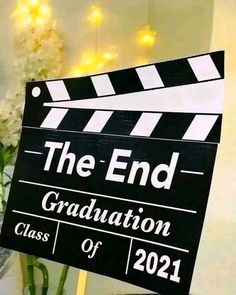 a black and white sign that says the end graduation class of 2021 with flowers in the background