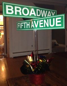 there is a street sign that says broadway and fifth avenue in front of a table