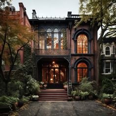 a large house with lots of windows and plants on the front steps, surrounded by trees