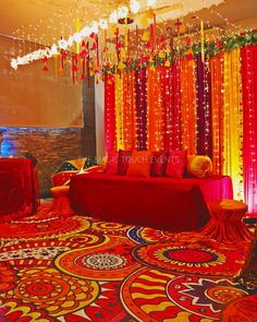 a room decorated in bright colors with red, yellow and orange drapes hanging from the ceiling