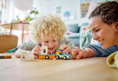 a woman and child playing with toys on the floor