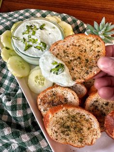 a person is dipping sauce on some bread with cucumbers and pickle slices