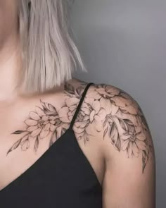 a woman's shoulder with flowers and leaves on the back of her neck,