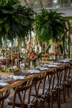 a long table is set with place settings and flowers in vases on the tables