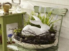 a white rabbit sitting in a nest on top of a table next to a green chair