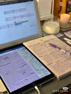 an open laptop computer sitting on top of a desk next to a pile of papers