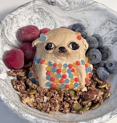 a bowl filled with fruit and a cake shaped like a dog sitting on top of it