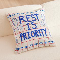 a pillow that says rest is priority on the back of a couch with eyes drawn on it