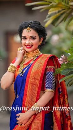 a woman in a blue and orange sari with gold jewelry on her neck posing for the camera