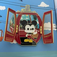 a mickey mouse pin sitting on top of a blue wall next to a cable car