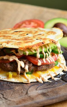 a close up of a sandwich on a cutting board with an avocado in the background