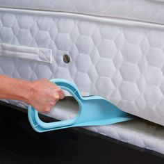 a person is opening the bottom of a mattress with a blue plastic handle on it