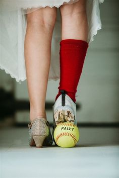 a woman's feet in high heels standing next to a baseball and softball ball