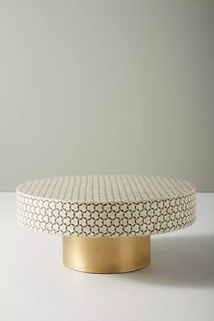 a white and gold coffee table sitting on top of a white counter next to a gray wall