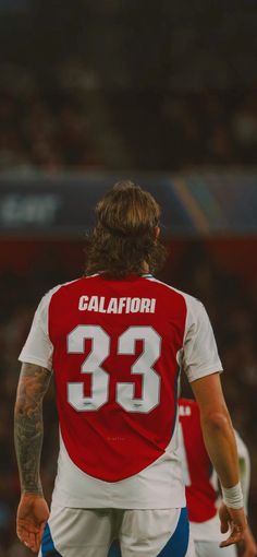 a soccer player with his back to the camera, wearing a red and white uniform