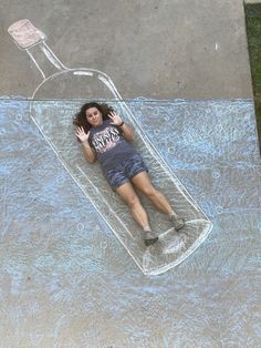 a woman laying on top of a chalk drawing in the shape of a wine bottle