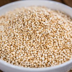 a white bowl filled with sesame seeds on top of a wooden table