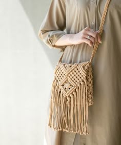 a woman is holding a handbag in her right hand and wearing a beige shirt