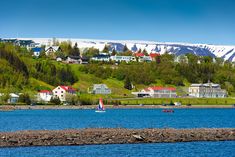 a lake with houses and boats in the water near snow covered mountain range behind it