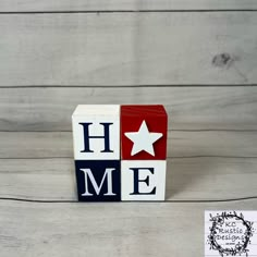 a red, white and blue block with the word home on it sitting next to a piece of paper