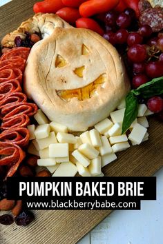 a pumpkin baked brie surrounded by cheese, crackers, and other food items